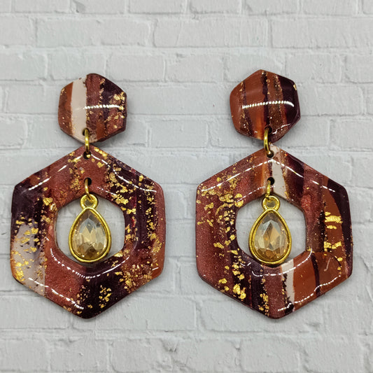 Hexagonal earrings with gold accents on a textured gray background