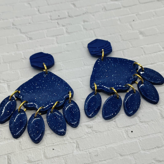 Blue earrings with gold accents on a textured white surface
