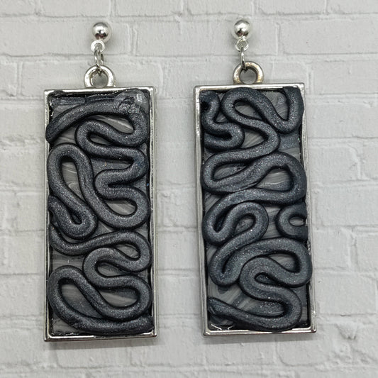 Pair of rectangular earrings with wavy pattern on a textured gray background