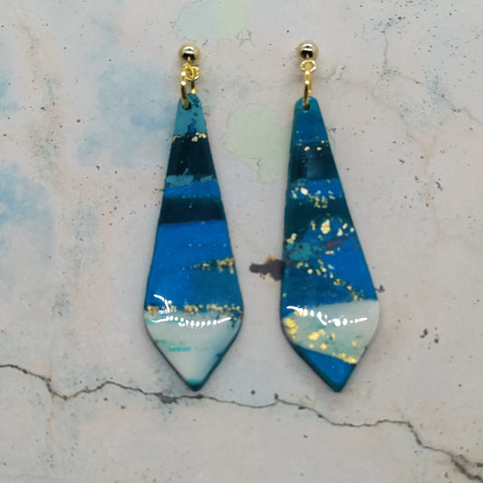 Blue and gold teardrop earrings on a textured surface