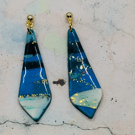 Pair of blue and gold earrings on a textured surface