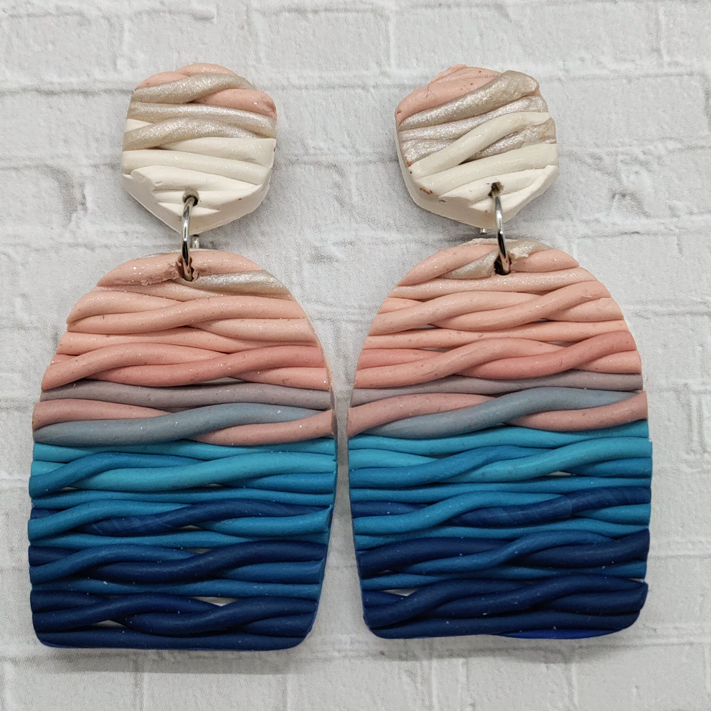 Pair of earrings with wavy, multicolored design on a textured white background