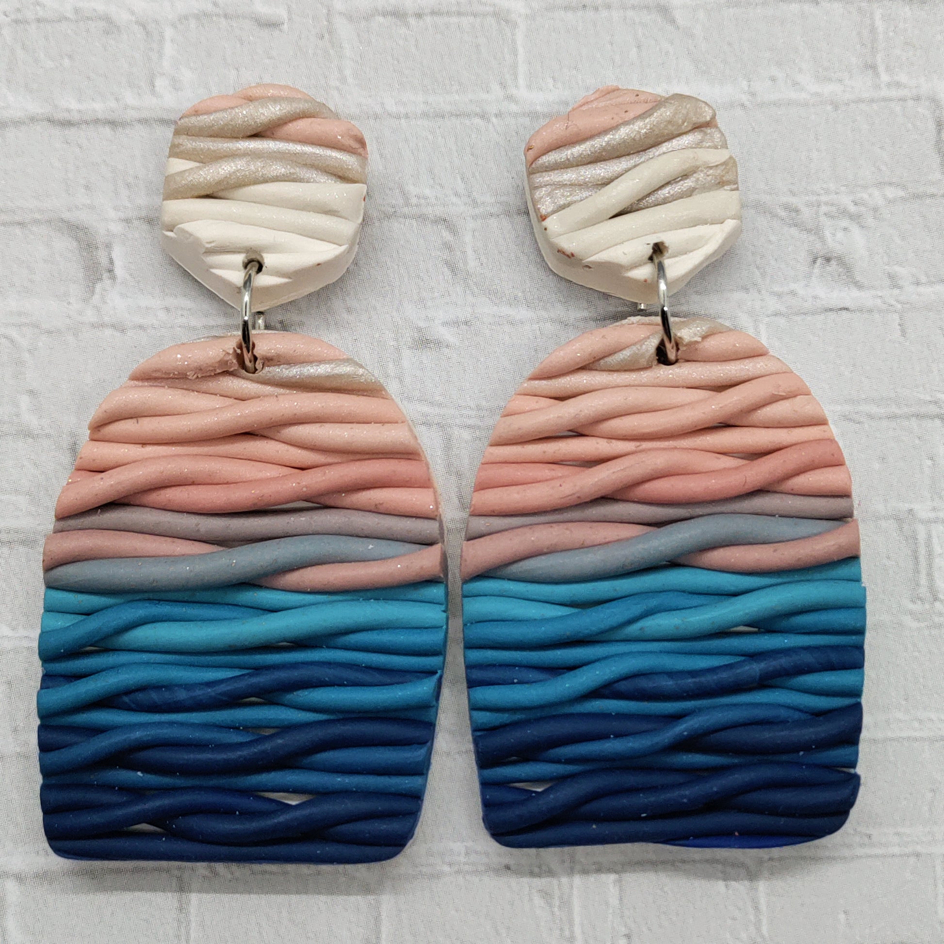 Pair of earrings with wavy, multicolored design on a textured white background