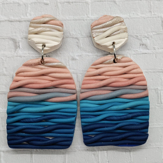 Pair of earrings with wavy, multicolored design on a textured white background
