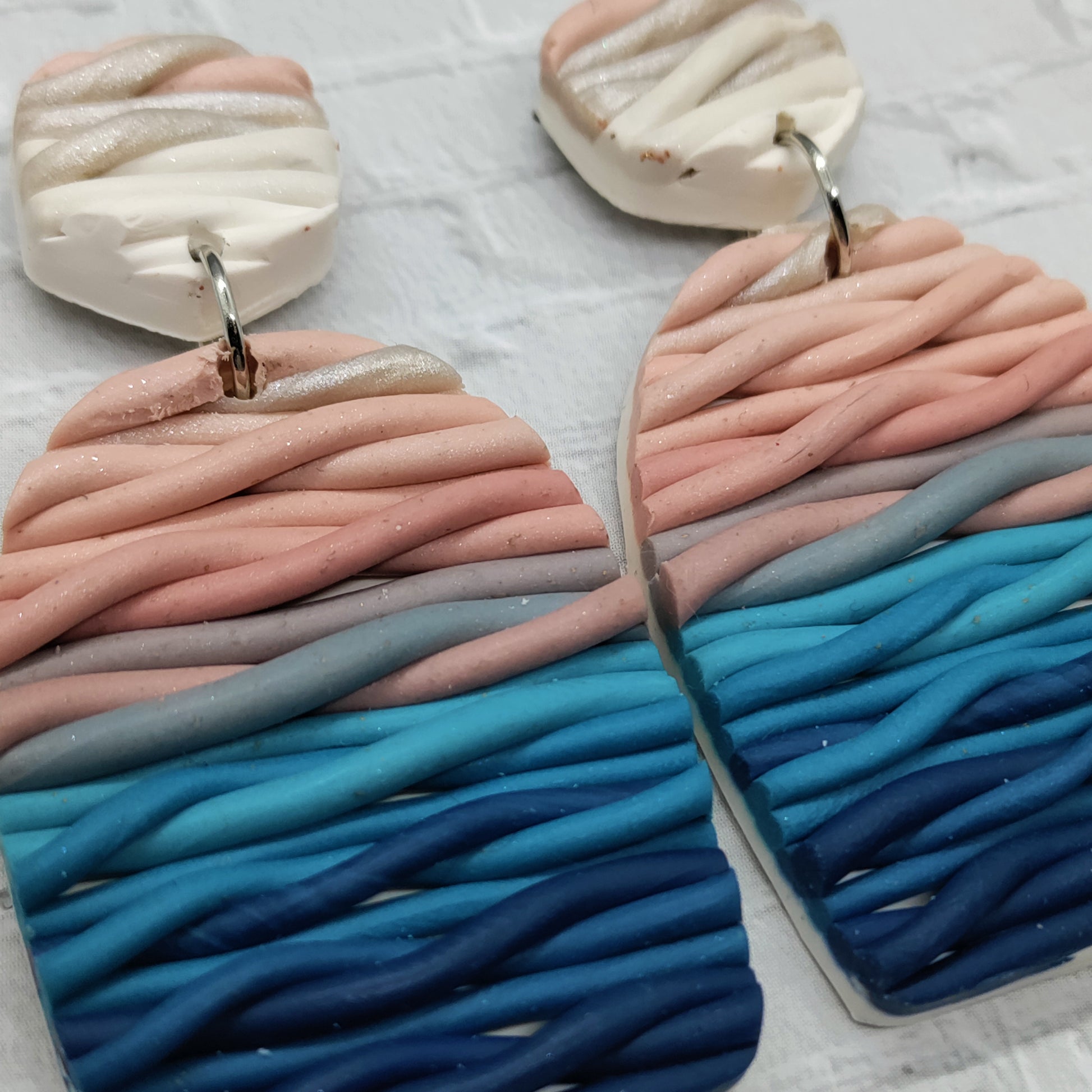 Pair of earrings with wavy, multicolored design on a light background