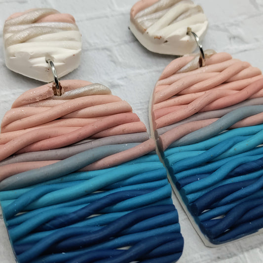 Pair of earrings with wavy, multicolored design on a light background