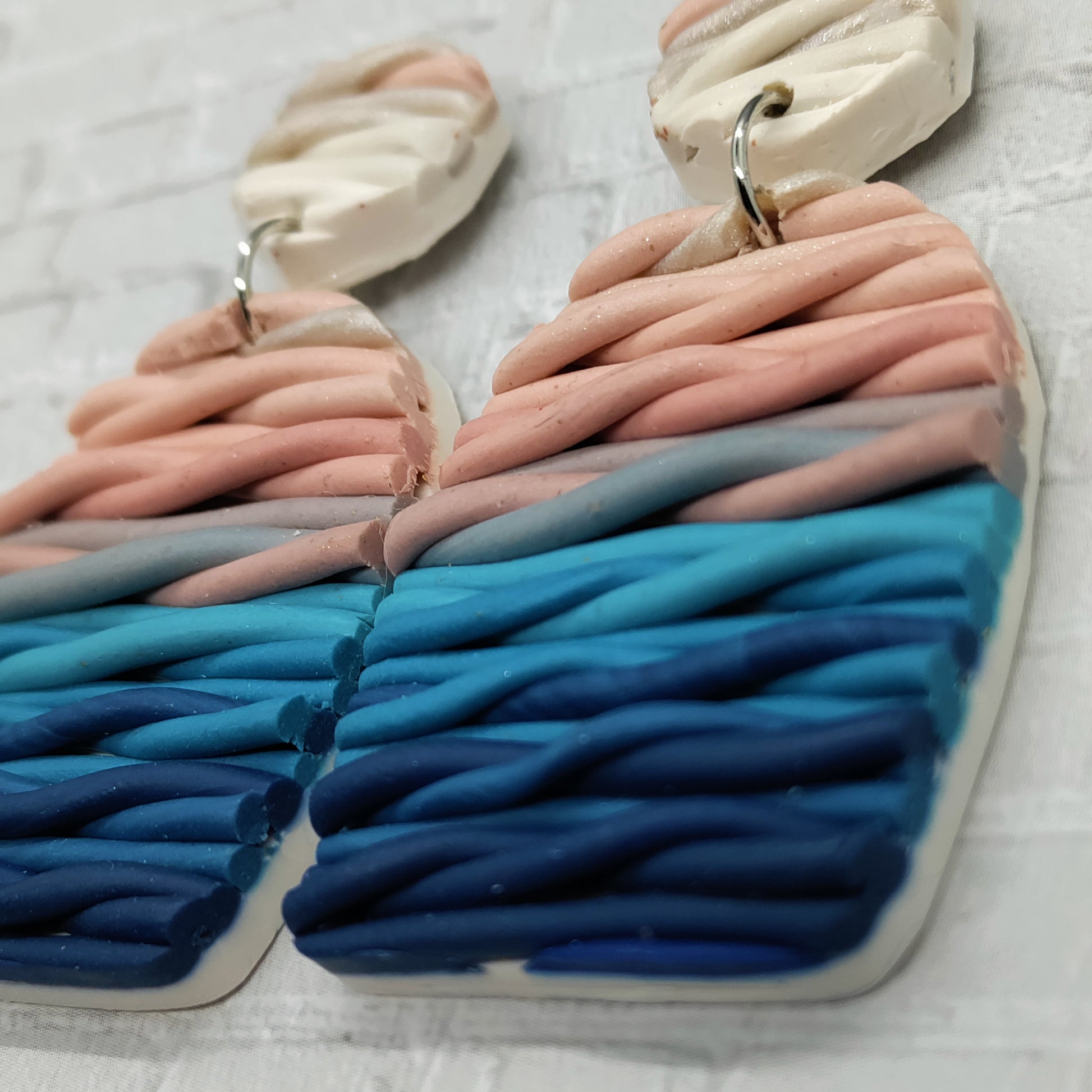 Pair of sandals with braided design in pink, blue, and gray on a light background