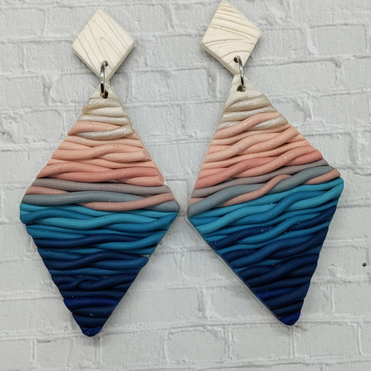 Pair of colorful earrings with wavy pattern on a textured gray background