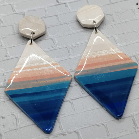 Triangular earrings with striped design on a textured surface