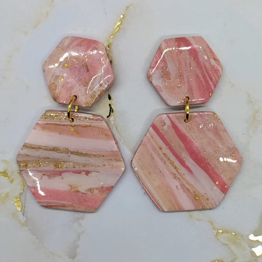 Hexagonal pink and gold earrings on a marble surface