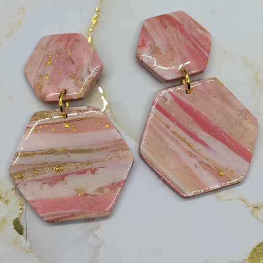 Pink marbled earrings with gold accents on a marble surface