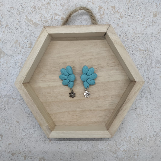 Hexagonal wooden tray with blue floral earrings on a textured surface