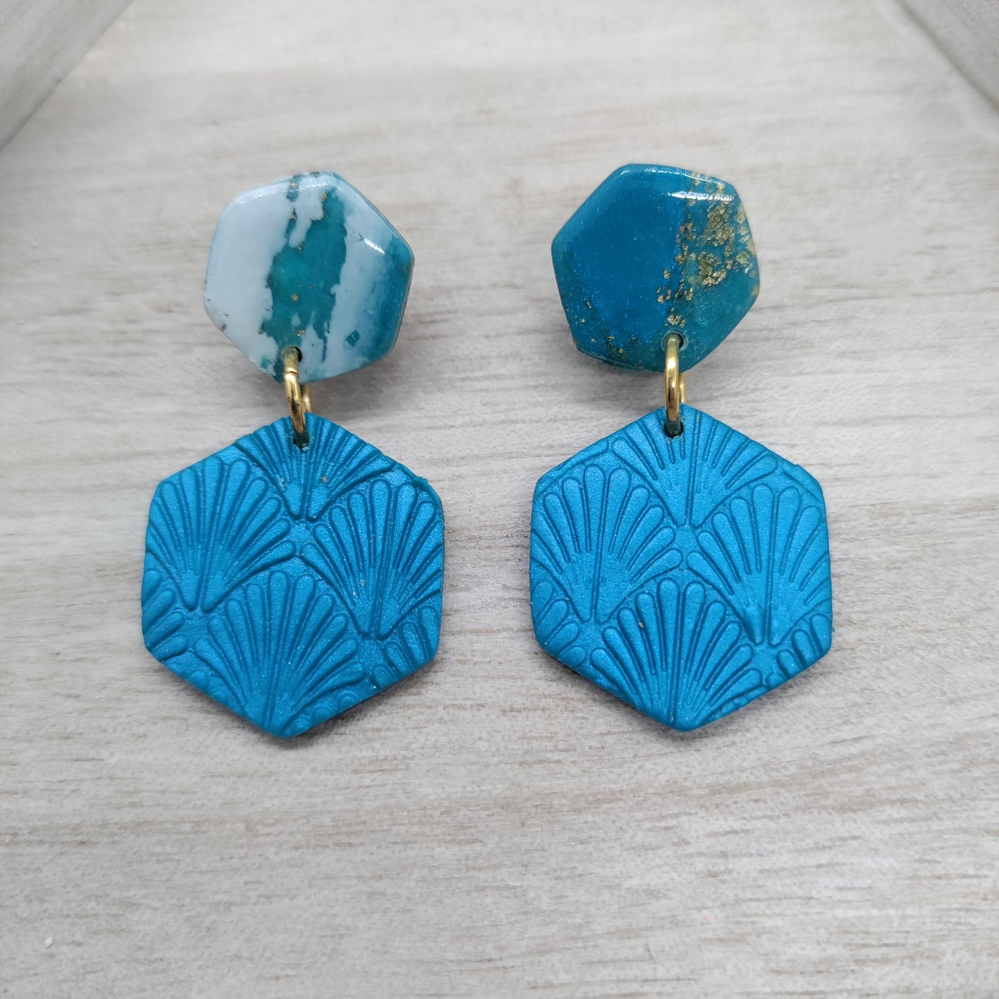 Pair of blue geometric earrings on a light gray surface