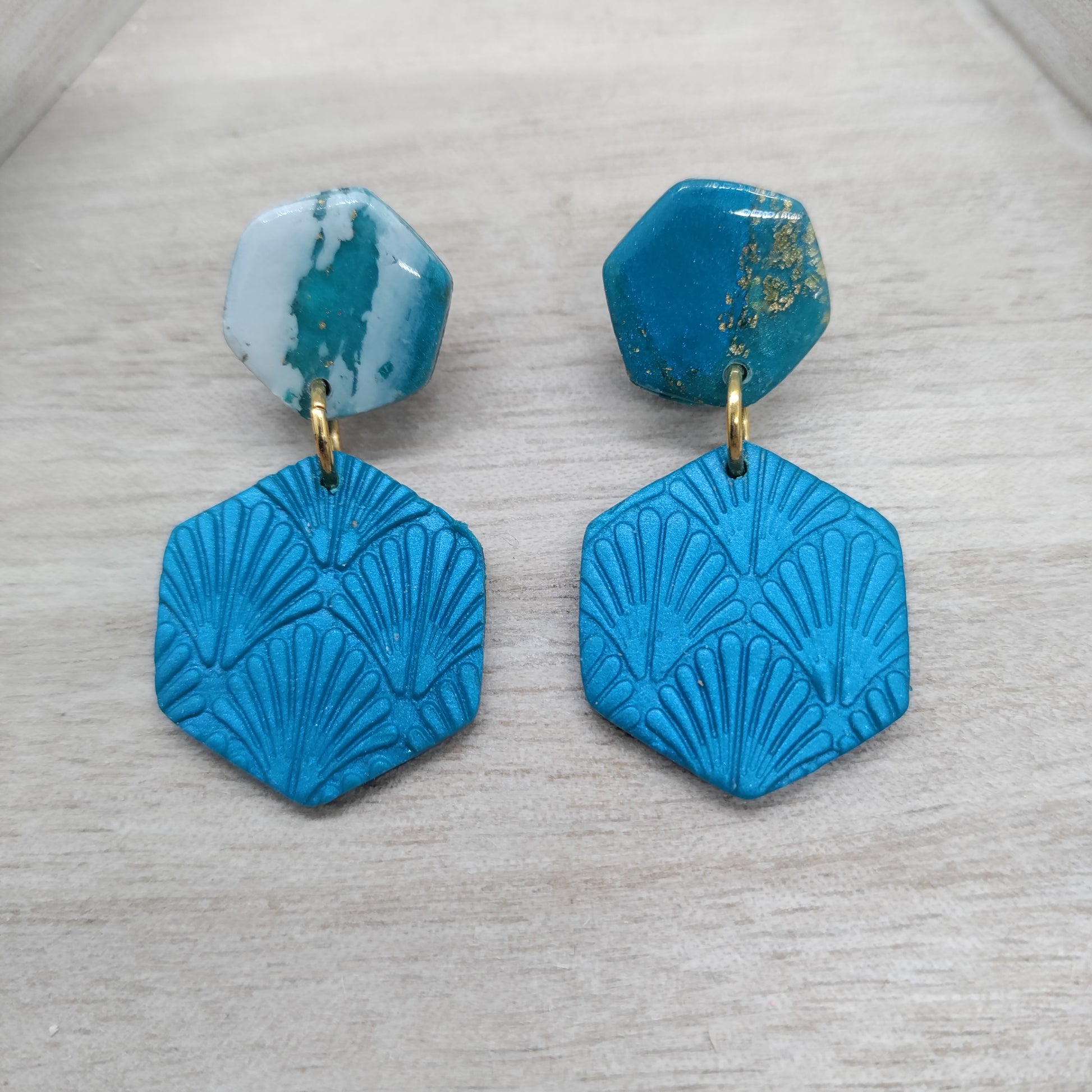 Pair of blue geometric earrings on a light gray surface