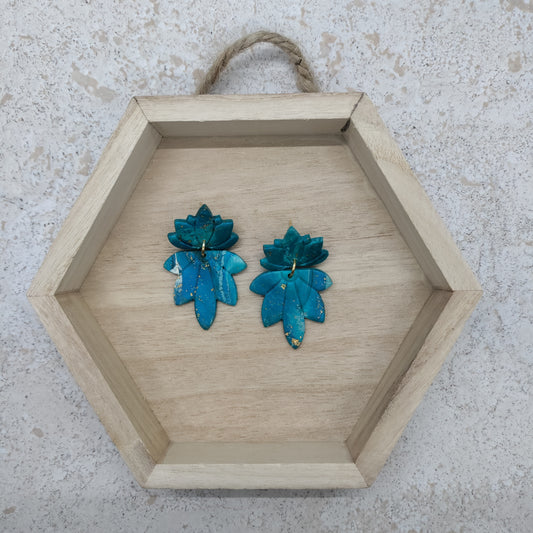 Hexagonal wooden tray with teal floral earrings on a textured surface