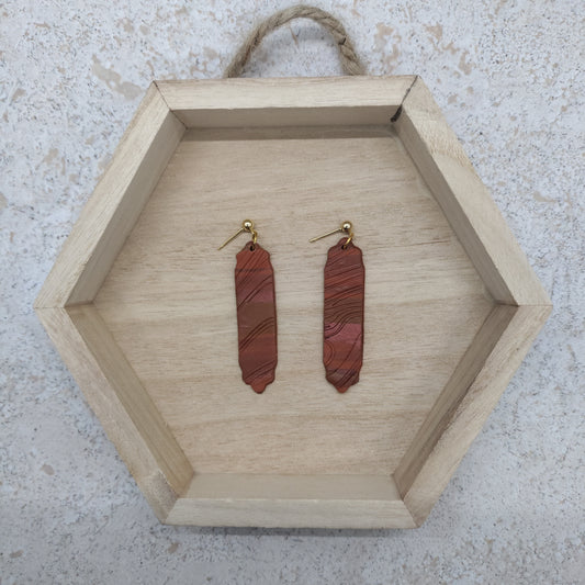 Wooden hexagonal tray with red stone earrings on a textured surface