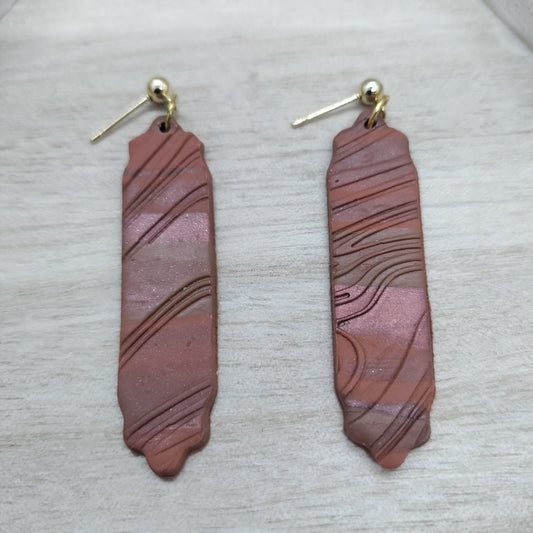 Pair of pink and brown striped earrings on a light gray background