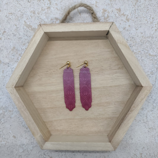 Pink earrings on a wooden hexagonal tray with a textured background
