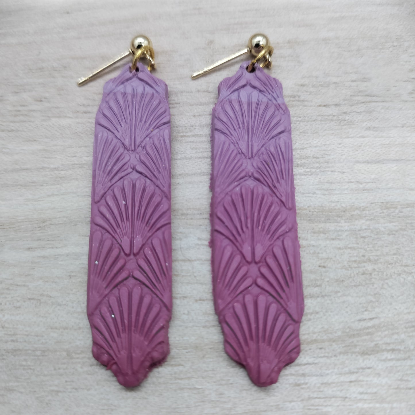 Purple earrings with gold hooks on a light gray background