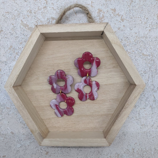 Hexagonal wooden tray with pink floral earrings on a textured surface