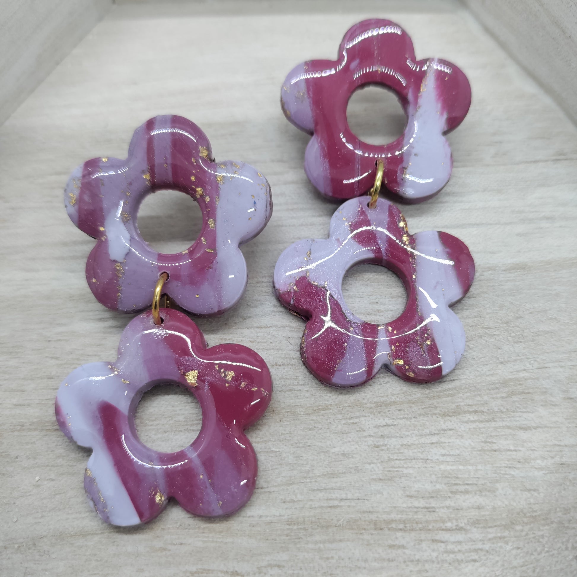 Set of four pink and white flower-shaped earrings on a light gray surface.