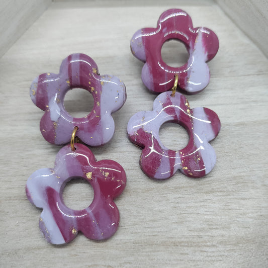 Set of four pink and white flower-shaped earrings on a light gray surface.