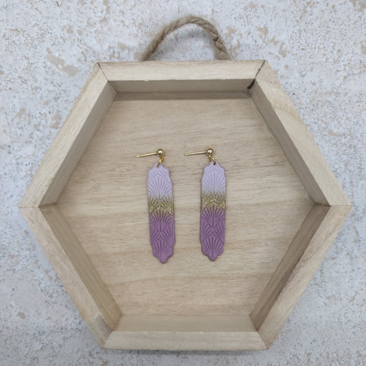 Pair of earrings on a wooden hexagonal tray with a textured background