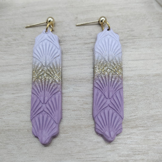 Pair of purple feather-shaped earrings with gold gradient on a light gray background