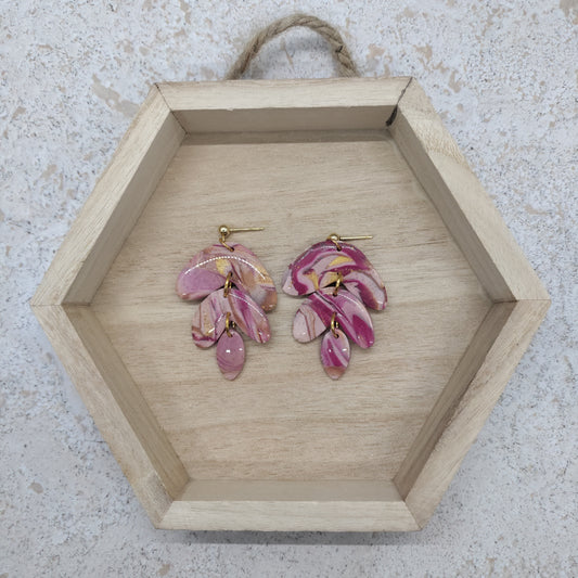 Pink floral earrings on a wooden hexagonal tray with a textured background