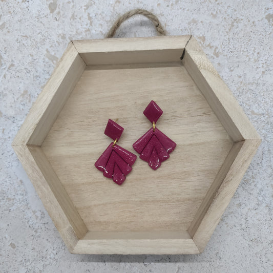 Hexagonal wooden tray with pink earrings on a light stone background