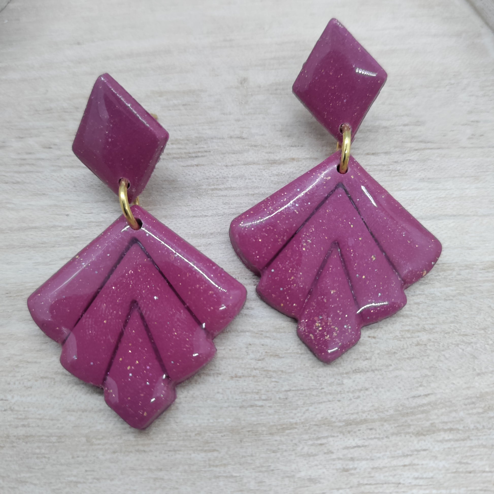 Pair of pink earrings with gold accents on a light gray background