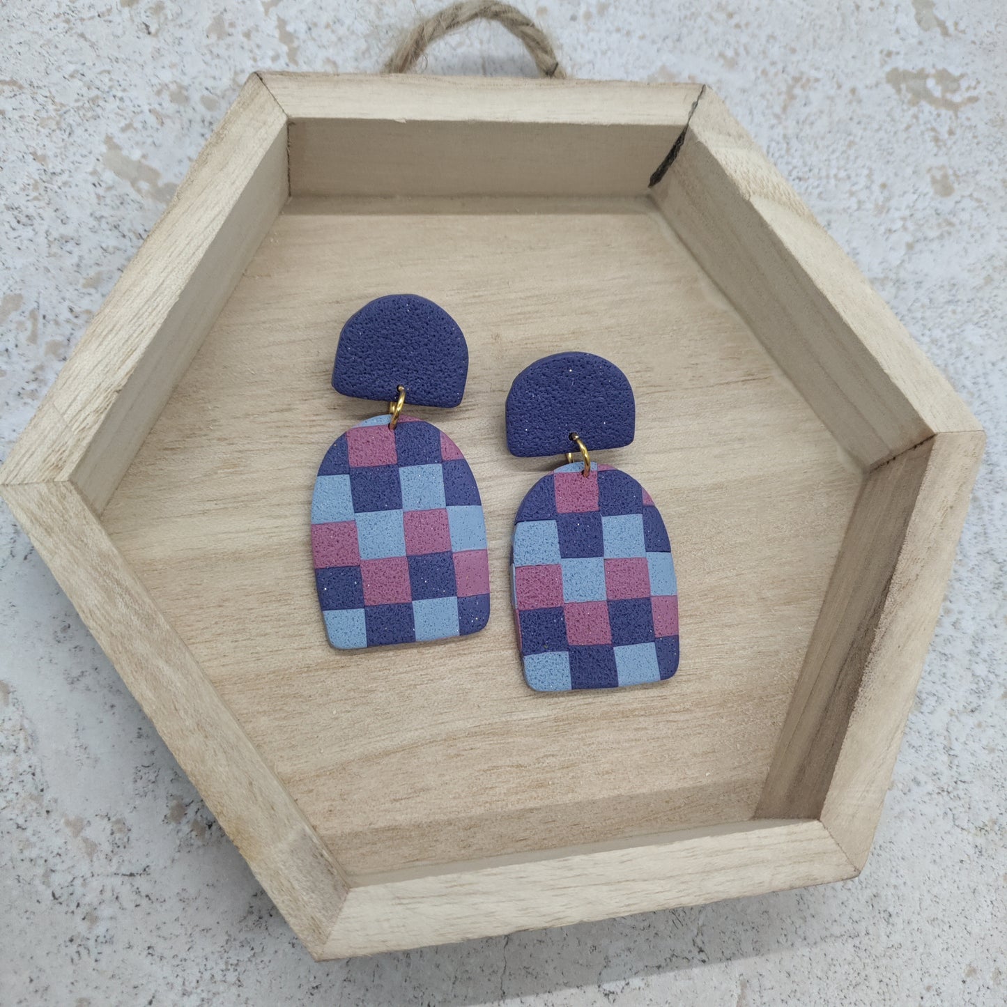 Pair of checkered earrings on a wooden hexagonal tray.