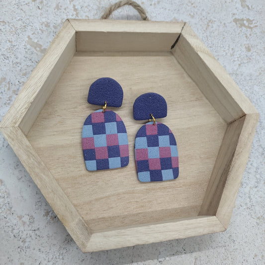 Pair of checkered earrings on a wooden hexagonal tray.