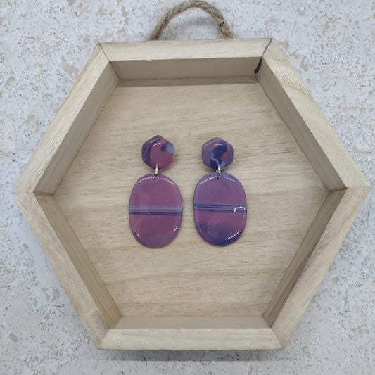 Hexagonal wooden tray with purple earrings on a textured surface