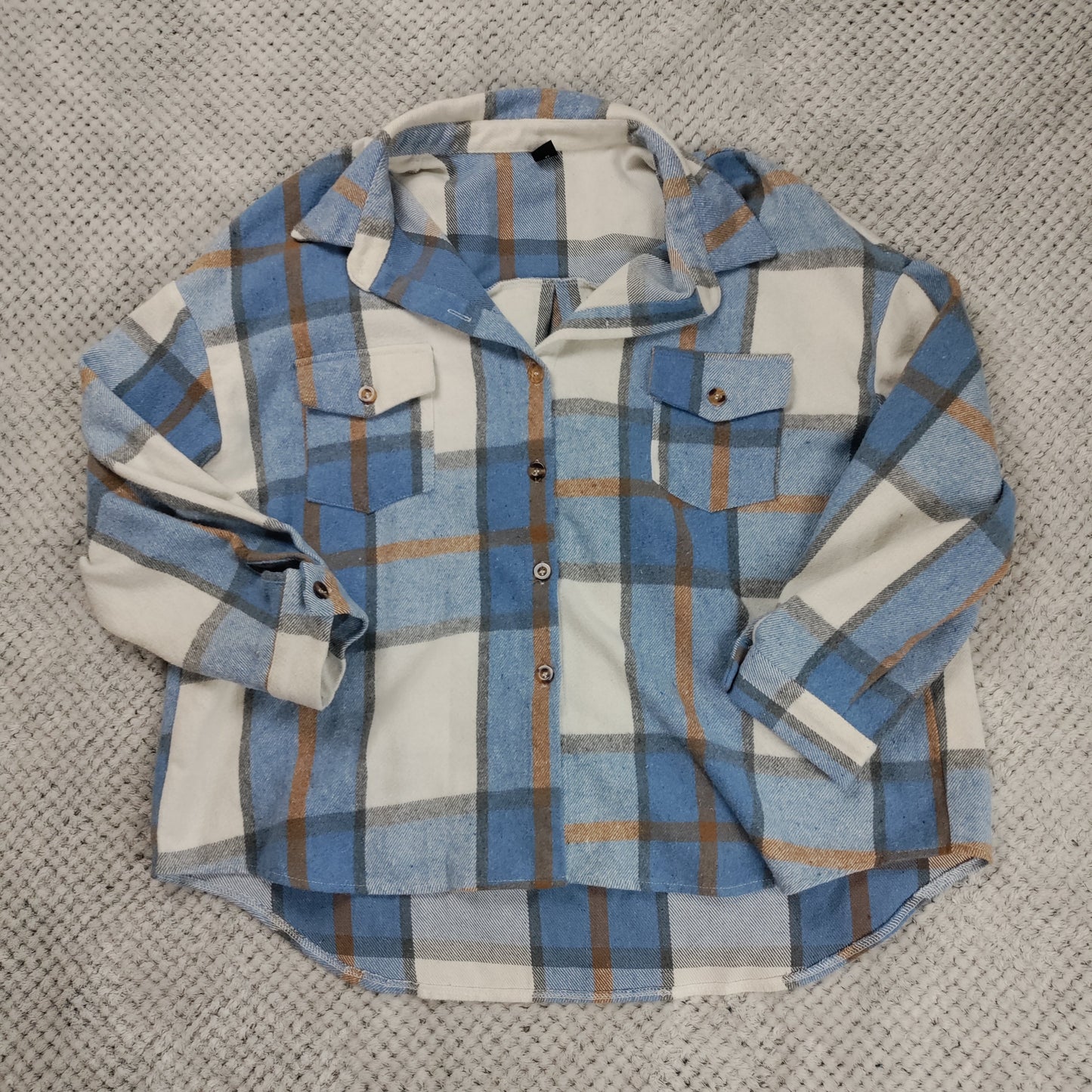 Plaid shirt with blue, white, and brown pattern on a textured surface