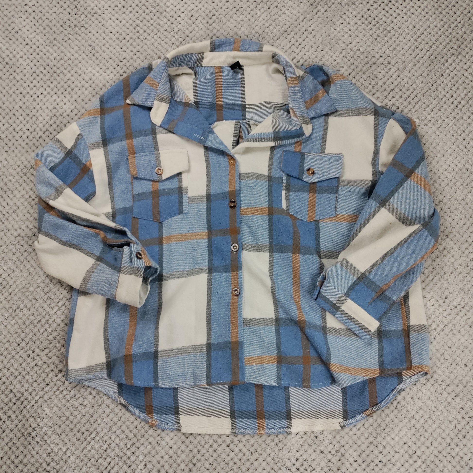 Plaid shirt with blue, white, and brown pattern on a textured surface