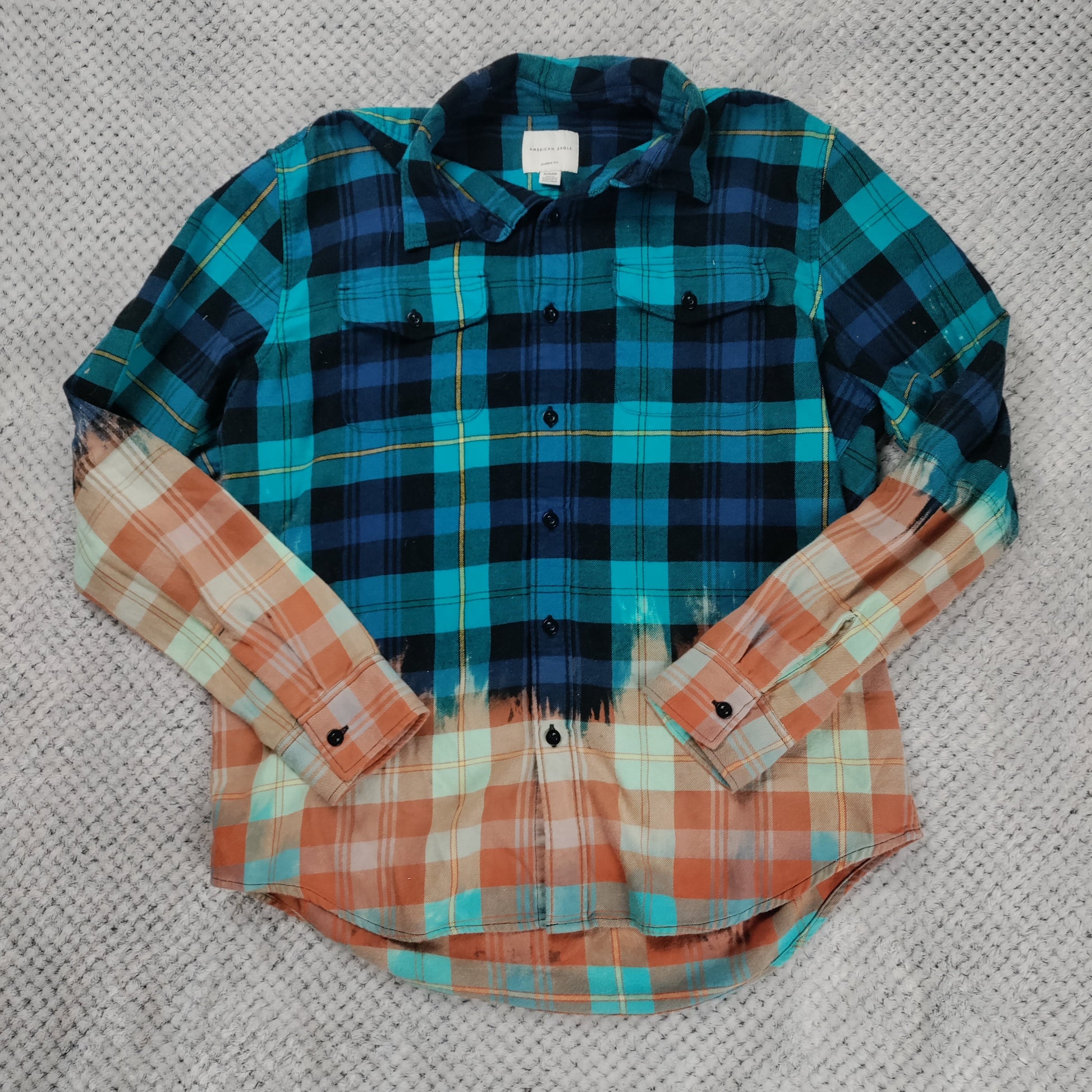 Plaid shirt with blue, green, and orange pattern on a textured gray background