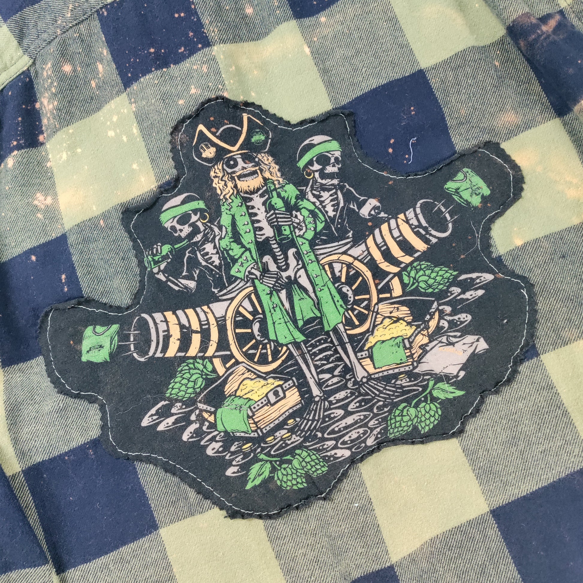 Checkered shirt with a pirate-themed patch featuring skeletons and barrels.