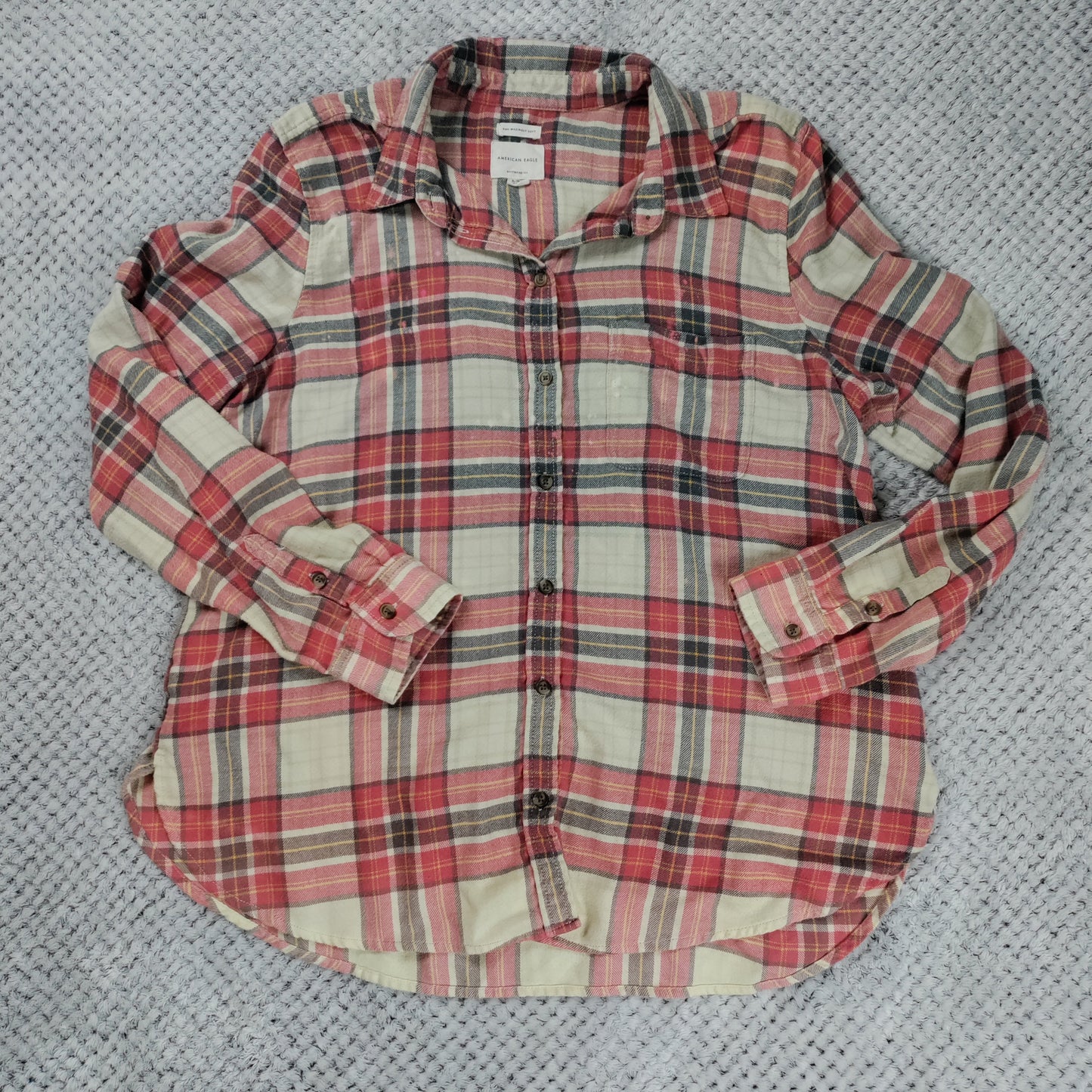 Plaid shirt with rolled-up sleeves on a textured gray background