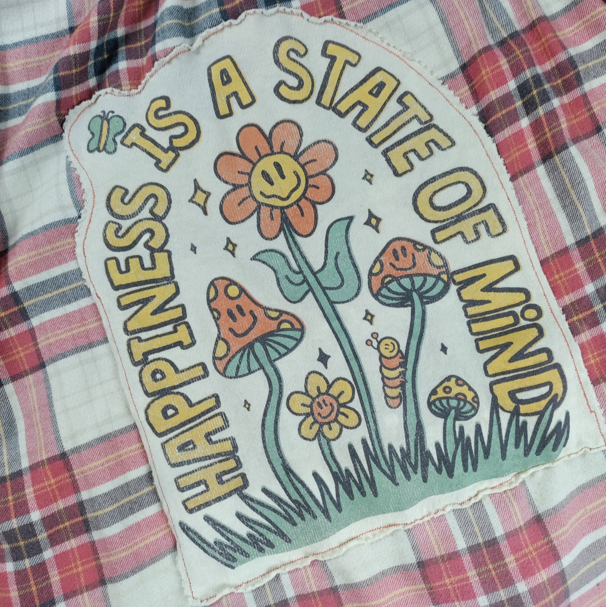 Floral patch with 'Happiness is a State of Mind' text on plaid fabric
