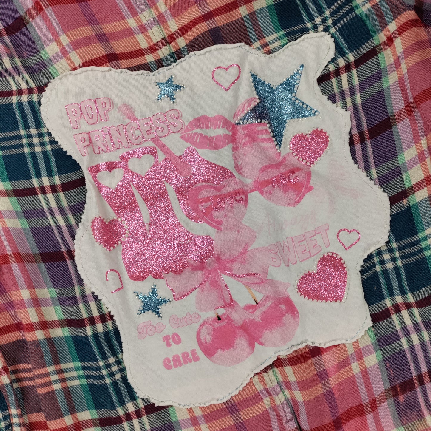 Decorative patch with pink graphics and text on a plaid fabric background