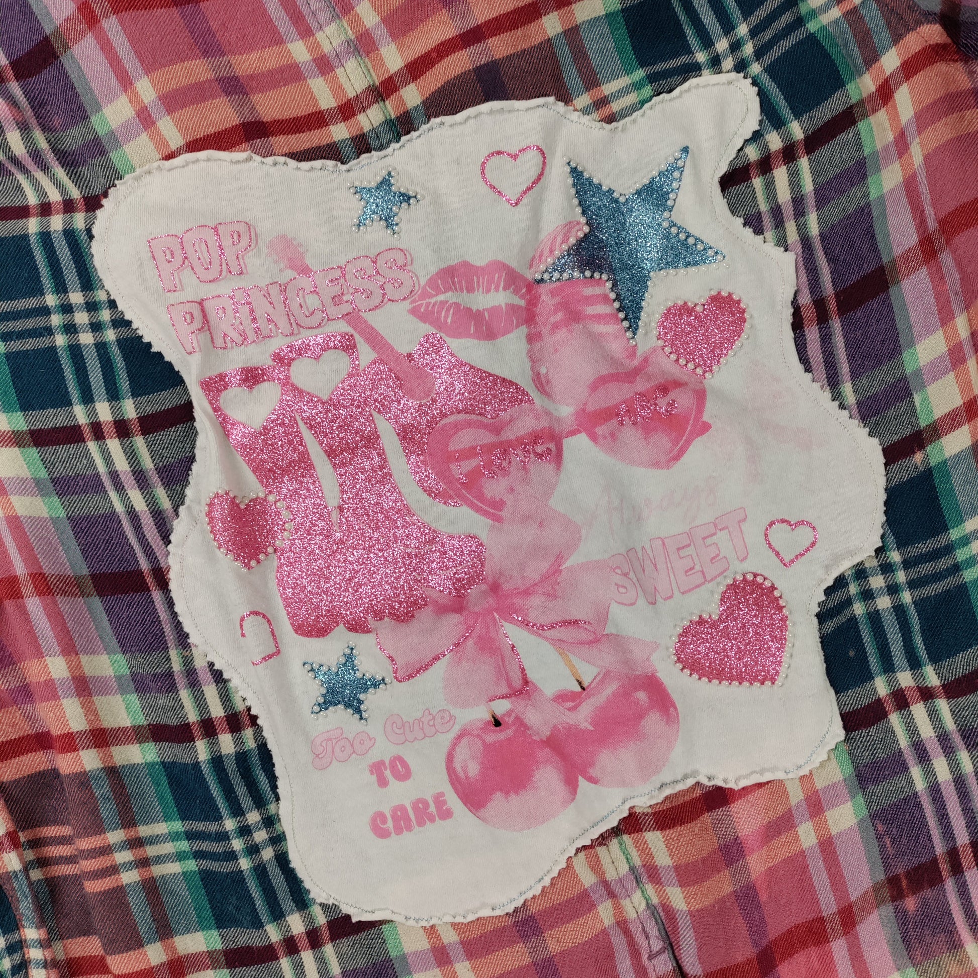Decorative patch with pink graphics and text on a plaid fabric background