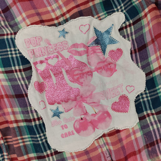Decorative patch with pink graphics and text on a plaid fabric background