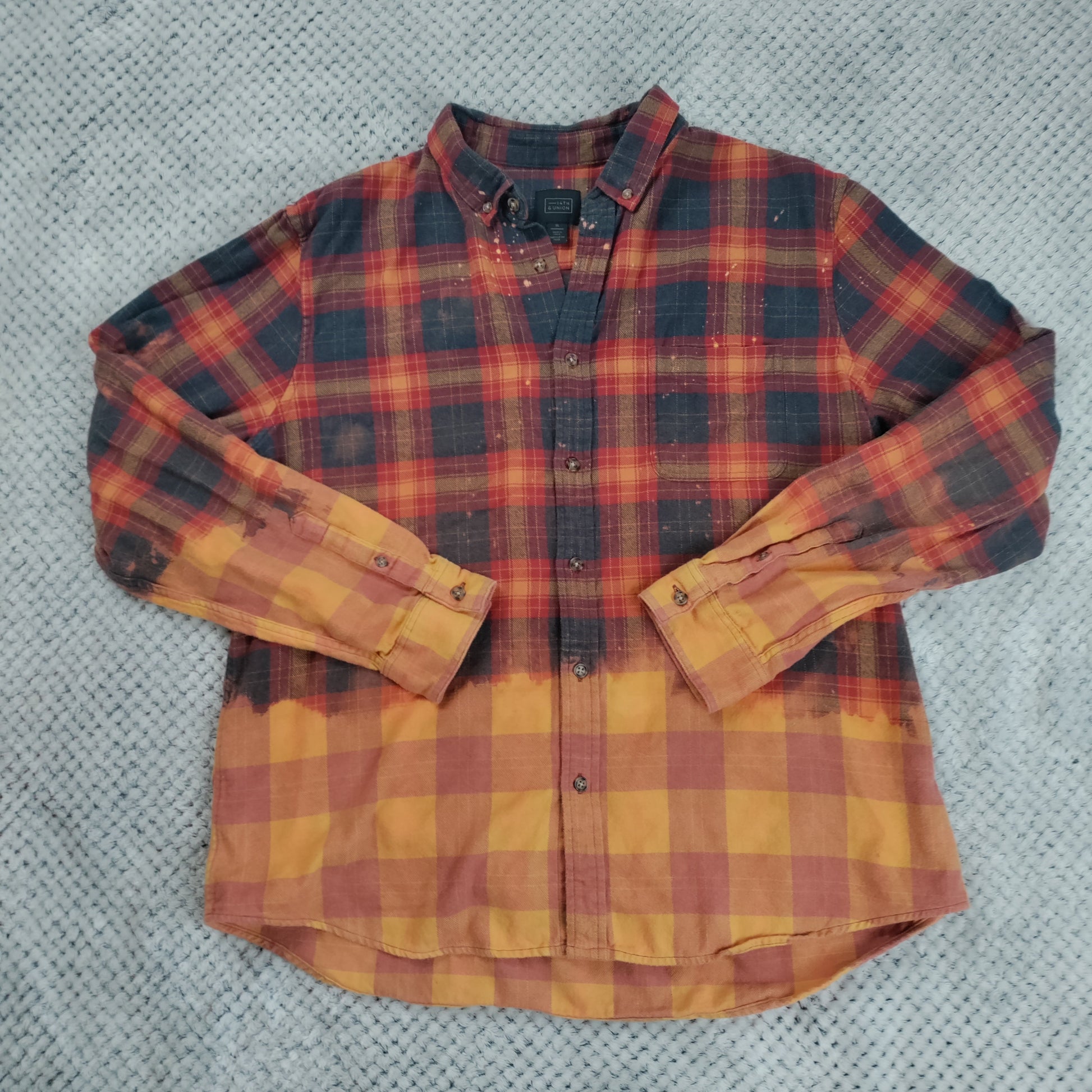 Plaid shirt with red and yellow pattern on a textured gray background
