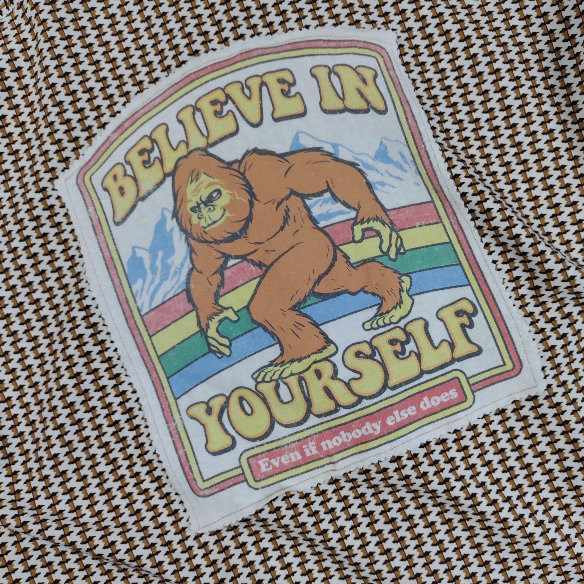 Sticker with a Sasquatch graphic and 'Believe in Yourself' text on a textured fabric background