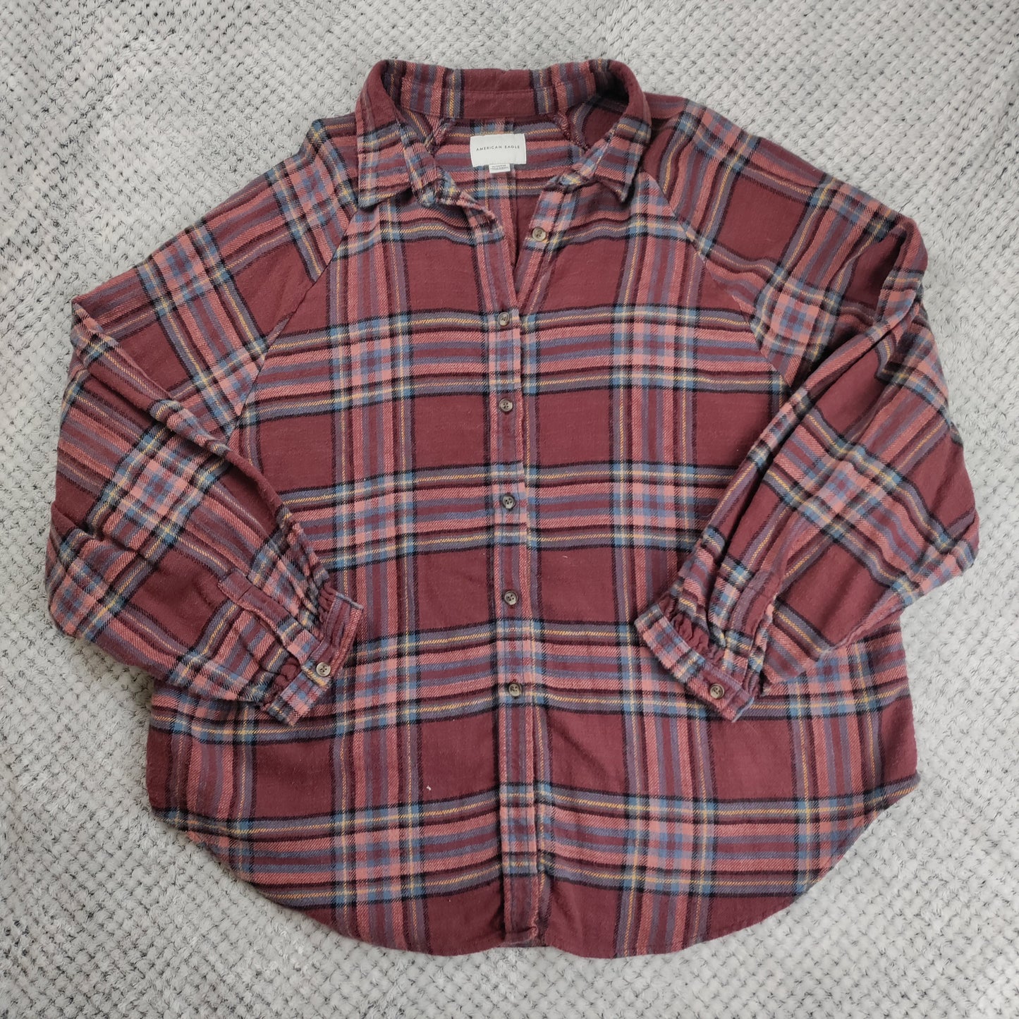 Plaid shirt with rolled-up sleeves on a textured surface