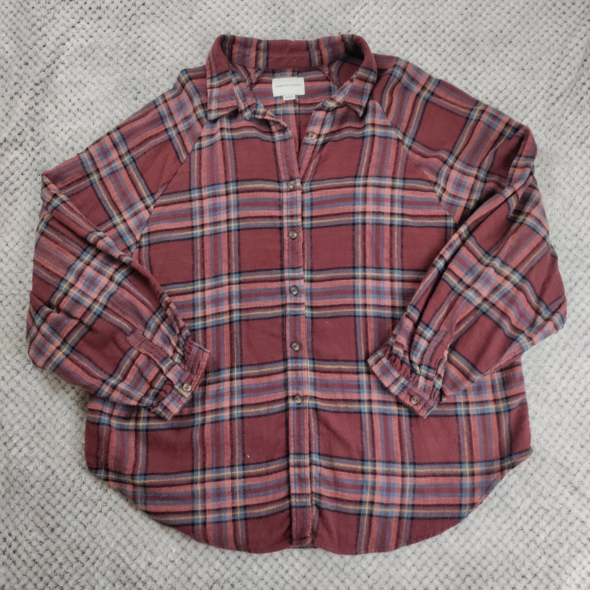 Plaid shirt with rolled-up sleeves on a textured surface