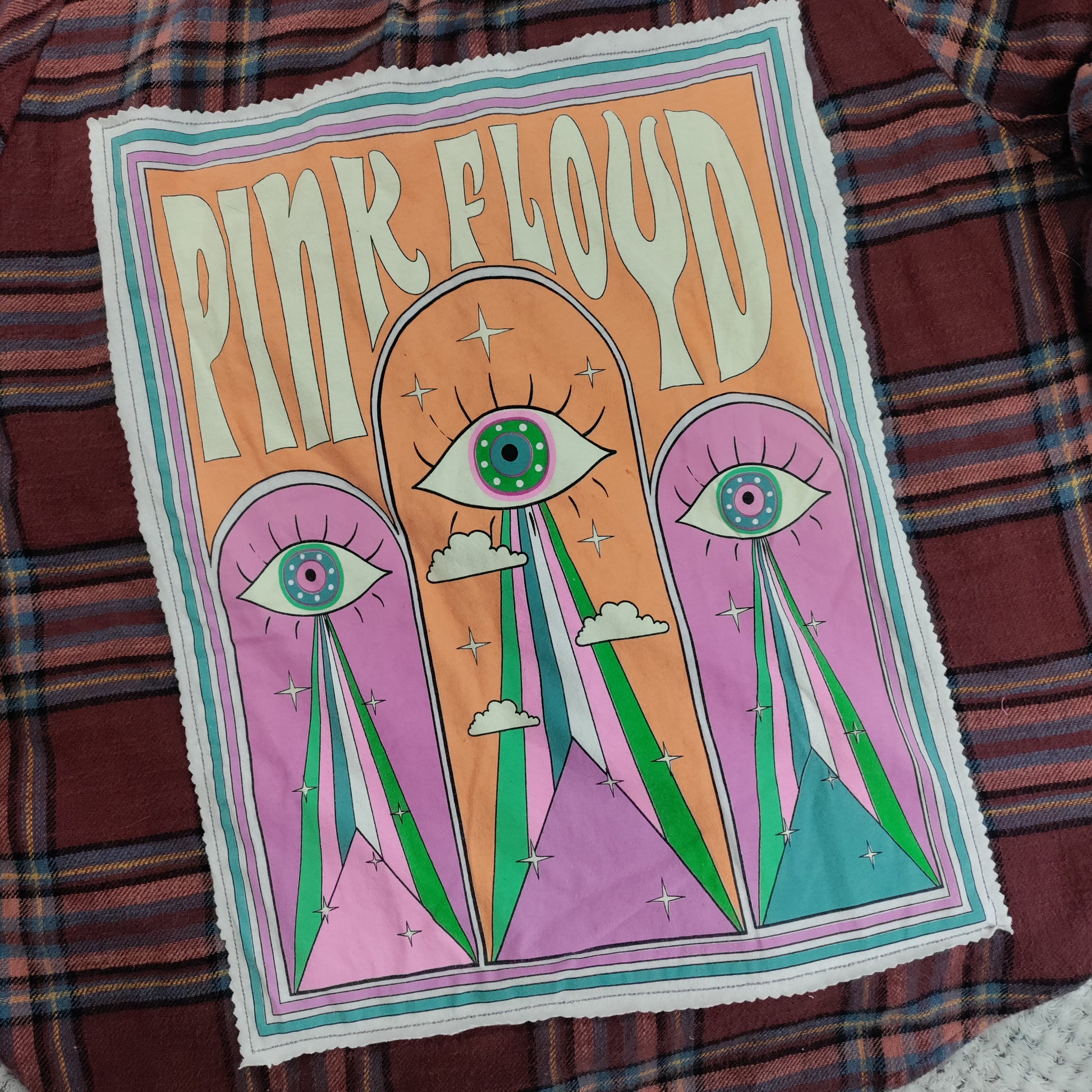 Pink Floyd poster with eye design on a plaid fabric background