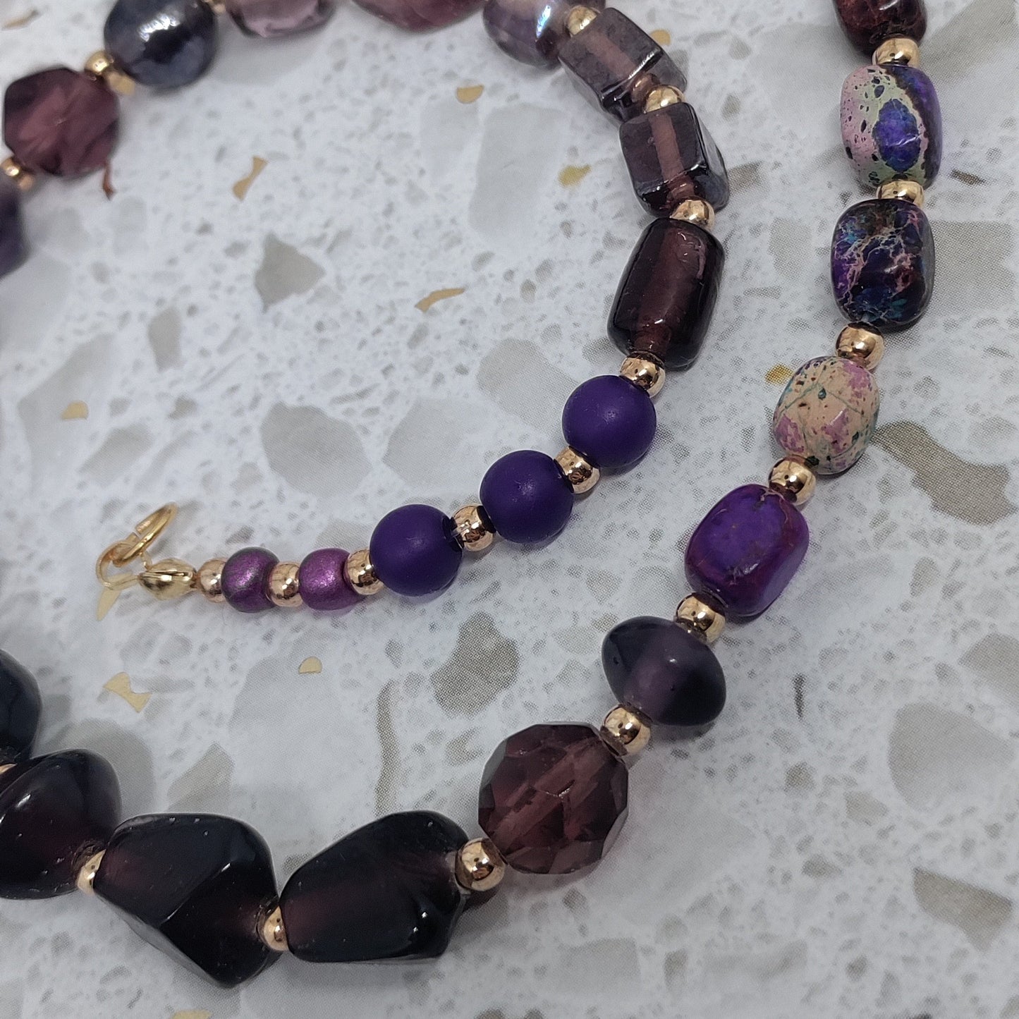 Necklace with purple and black beads on a textured surface