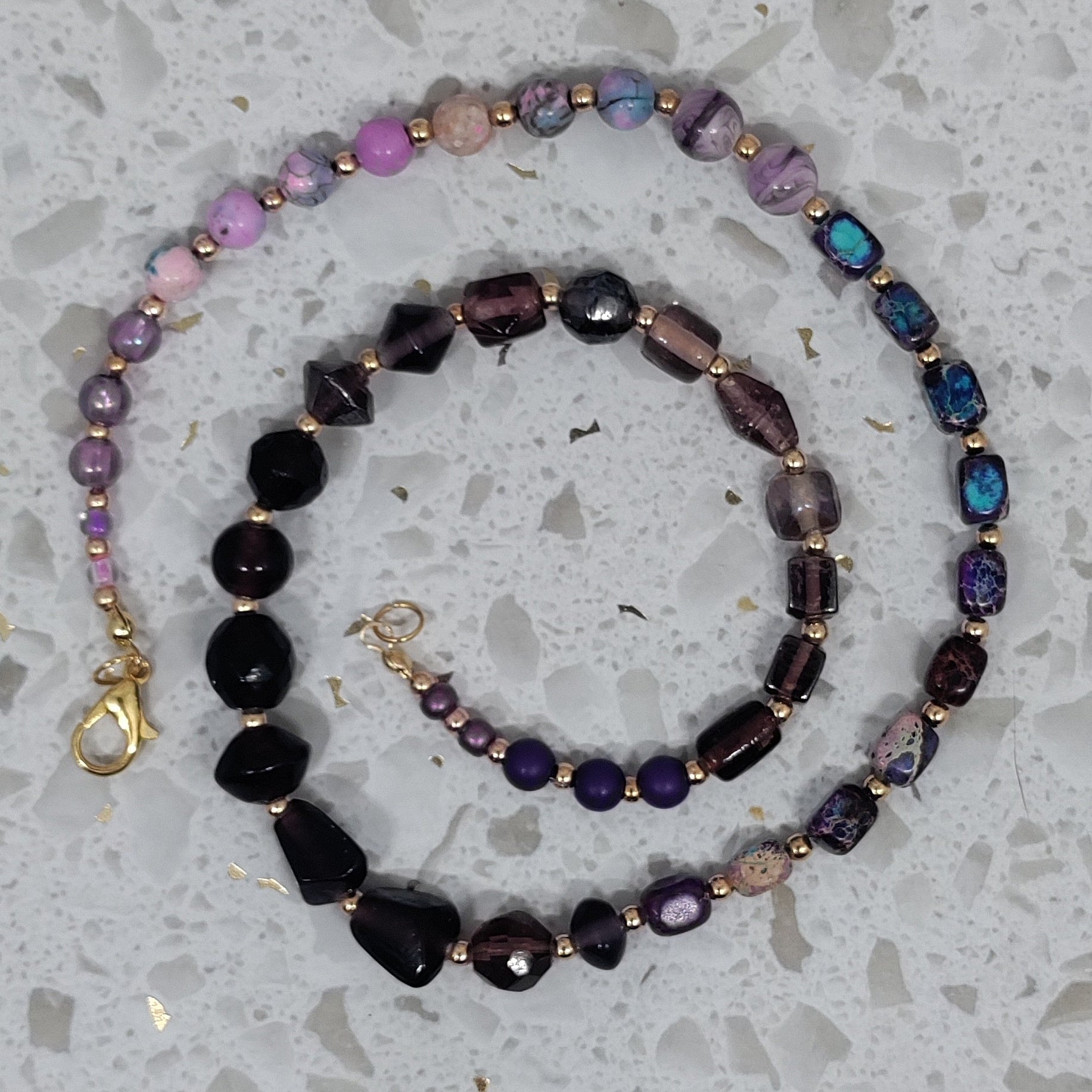 Set of beaded necklaces on a speckled gray surface